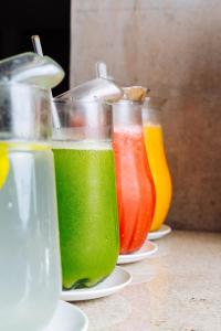 three different colored juices sitting on plates on a table at Cris Hotel in Florianópolis