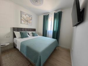 a bedroom with a bed with green sheets and a window at Apartments SORELLE in Podstrana