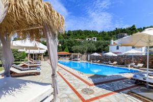 a large swimming pool with chairs and umbrellas at Ourania Studios & Apartments in Skopelos Town