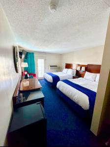 two beds in a hotel room with blue carpet at Islander Inn in Put-in-Bay