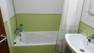 a green bathroom with a sink and a bath tub at Peñisqueira in Ribeira