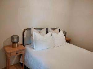 a bedroom with a bed with white pillows and a table at Maisonnette de charme A 5 min du Parc PUYDUFOU in Les Épesses