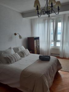 1 dormitorio con 1 cama blanca grande con lámpara de araña en Villa Chati, en Santander