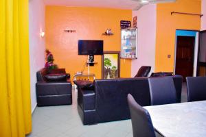 uma sala de espera com sofás e uma televisão de ecrã plano em Chez mimi em Cotonou