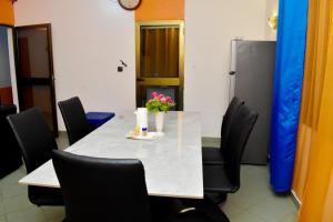 una mesa de comedor con sillas y flores. en Chez mimi en Cotonú