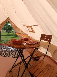 a table with wine glasses and a chair in a tent at Tente mongole " ô Rêves Atypiques" in Boucé