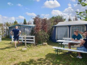 a group of people sitting at a picnic table in front of a caravan at Camping - Park Władysławowo in Władysławowo