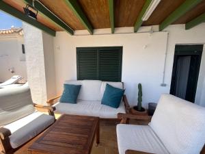 een veranda met een bank, 2 stoelen en een cactus bij Almadraba Suite Ático duplex in Zahara de los Atunes
