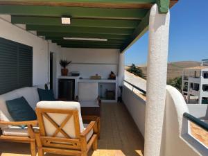 Almadraba Suite Ático duplex في ساهارا ذي لوس أتونِس: شرفة ذات سقف أخضر مع كراسي وطاولة