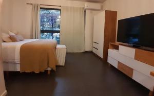 1 dormitorio con 1 cama y TV de pantalla plana en Cálido depto 2 personas- Zona residencial en Morón