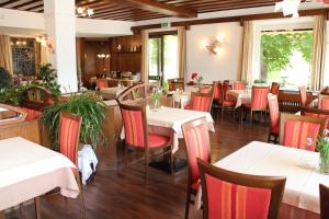 ein Restaurant mit weißen Tischen und roten Stühlen in der Unterkunft Aldranser Hof in Innsbruck