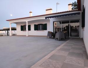 een wit huis met een grote patio met stoelen bij Luar dos Magos in Salvaterra de Magos