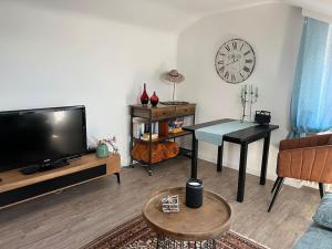 sala de estar con TV de pantalla plana y mesa en Gemütliches Apartment für Messe, Job & Kurzurlaub im Grünen, Nähe Düsseldorf, en Meerbusch