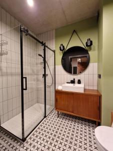 a bathroom with a shower and a sink and a mirror at Apartamenty LOFTykocin in Tykocin