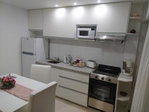 cocina pequeña con armarios blancos y fogones horno superior en 19 DE MAYO APARTMENT, en Bahía Blanca