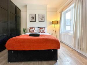 a bedroom with a large bed with a red blanket at Luxe & Stylish 1 Bed Flat in London