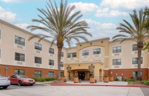 a hotel with palm trees in front of a building at Extended Stay America Suites - Orange County - Huntington Beach in Huntington Beach
