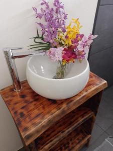 - un bol blanc avec des fleurs sur une table en bois dans l'établissement TEMAEVA LODGE, à Nuku Hiva