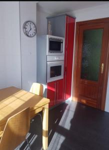 eine Küche mit einem Tisch und einer Uhr an der Wand in der Unterkunft Casa bella alma in Ramales de la Victoria