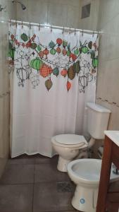 ein Badezimmer mit einem WC und einem Duschvorhang mit Sonnenschirmen in der Unterkunft Como en Casa in Posadas