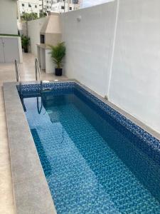 a swimming pool with blue tiles on the side of a building at Hermoso hogar con bbq y piscina en Punta Blanca in Punta Blanca