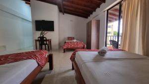 a hotel room with two beds and a television at Hotel Bahía Yubarta in Bahía Solano