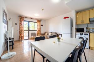 a kitchen and living room with a white table and chairs at Oasis Fuerteventura in Corralejo