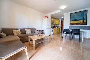 a living room with a couch and a table and a kitchen at Oasis Fuerteventura in Corralejo