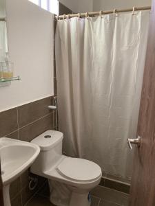 La salle de bains est pourvue de toilettes blanches et d'un lavabo. dans l'établissement Hermoso hogar con bbq y piscina en Punta Blanca, à Punta Blanca