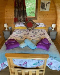 Bett in einem Zimmer mit lila Kissen darauf in der Unterkunft luxury pod with hot tub in Clodock