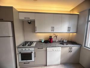 cocina con armarios blancos, fogones y fregadero en 300 meters to Konyaaltı beach 2+1 large and spacious apartment, en Antalya