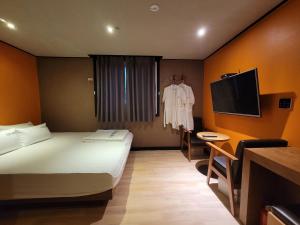 a hotel room with a bed and a tv at Foxy Hotel in Busan