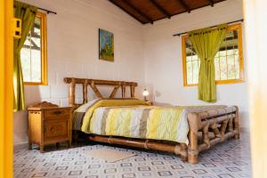 a bedroom with a bed and a table and windows at La Cabaña - Monte Jazmín in Pereira