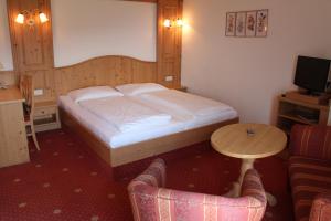 a bedroom with a bed and a table and a chair at Aldranser Hof in Innsbruck