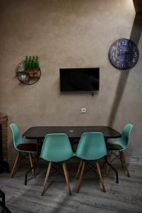 une table avec quatre chaises et une télévision murale dans l'établissement Susurros del Manadero, à Robledillo de Gata