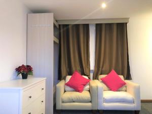 two pink pillows sitting on a chair in front of a window at Breeze Homstay in Tile Hill