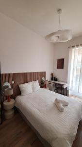 1 dormitorio con 1 cama blanca grande y escritorio en Appartement au calme T3 RDC - Quartier de France en Vichy