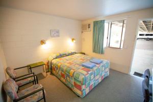 1 dormitorio con 1 cama y 2 sillas en Mitchell Motel & Cabin Park, en Mitchell