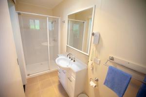 a white bathroom with a sink and a shower at Mitchell Motel & Cabins in Mitchell