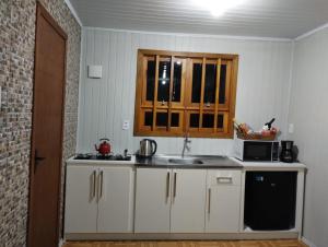 a kitchen with a sink and a microwave at Gramado Família in Gramado