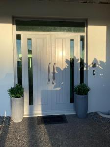 a white front door of a house with two potted plants at Bunker on Belt in New Plymouth