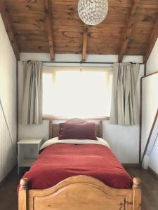 1 dormitorio con 1 cama con manta roja y ventana en Casa Mora en San Martín de los Andes