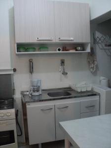 a kitchen with white cabinets and a sink at Apartamento Aconchegante in São Vicente