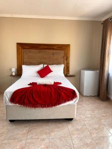 um quarto com uma cama com um cobertor vermelho em The Botanical Gardens em Rundu
