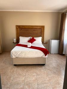 um quarto com uma cama com almofadas vermelhas e brancas em The Botanical Gardens em Rundu