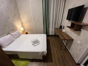 een kleine kamer met een bed en een televisie bij Hotel Goldenera in Koetaisi