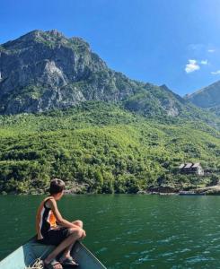 una persona sentada en un barco en un cuerpo de agua en Guest House Aprripe Guri, en Fierzë