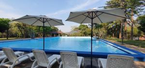 a group of chairs and umbrellas next to a swimming pool at Tower Suites in Paraguarí