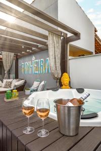Dois copos de vinho numa mesa de madeira ao lado de uma banheira em Pinheira Beach House com Jacuzzi em Palhoça