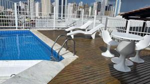 a deck with a table and chairs and a pool at Manaíra Flat 206 Em frente ao shopping Manaíra in João Pessoa